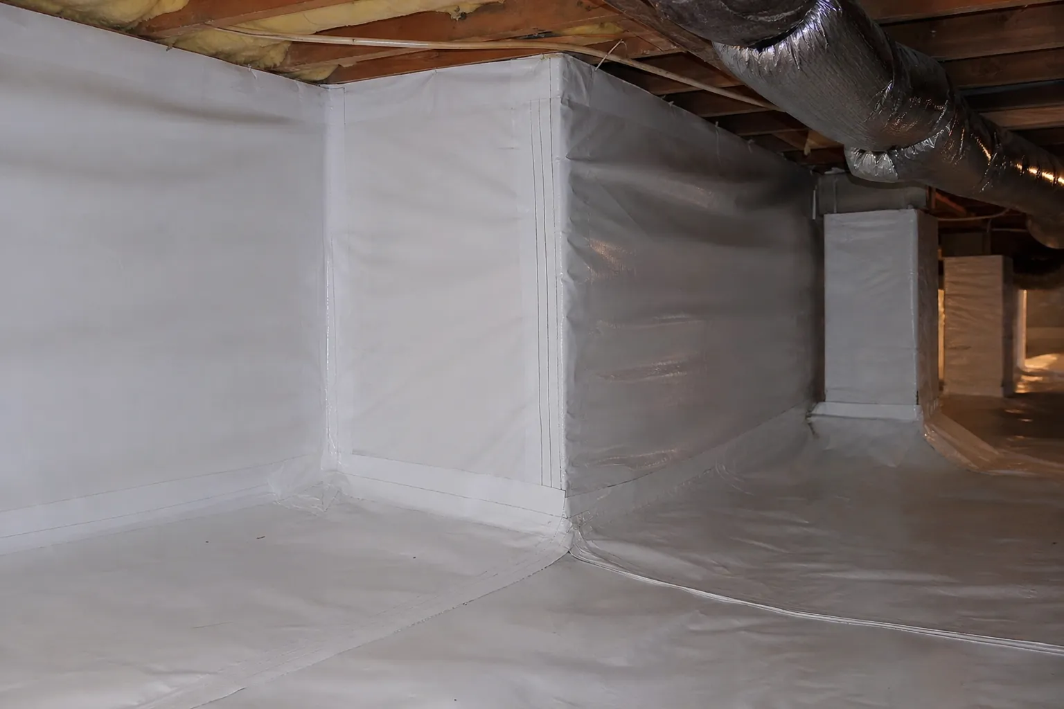 White crawl space liner covers the floor, walls and support piers, with visible seams beneath exposed joists and insulated ductwork.