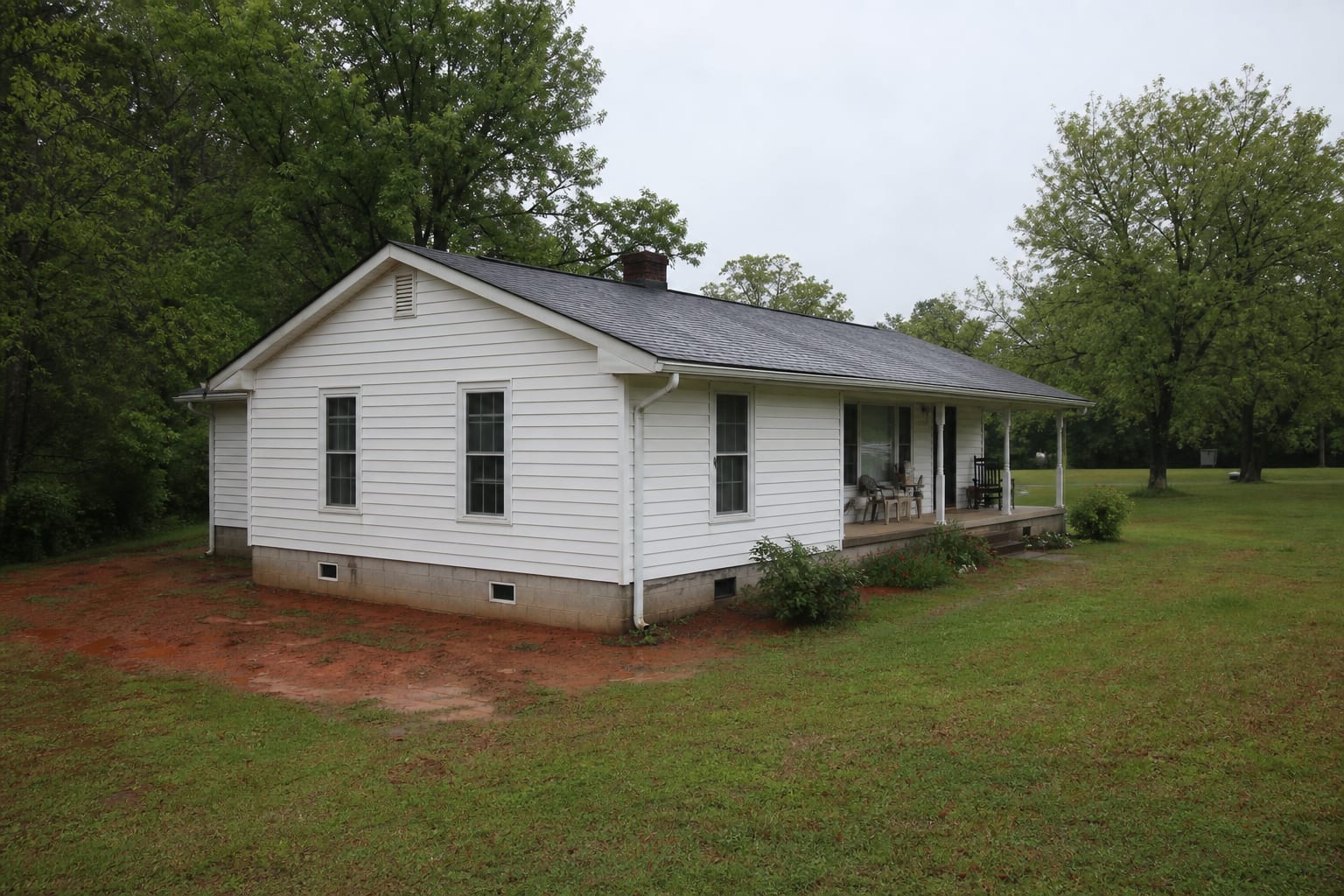Rural-edge ranch home with a vented crawl space foundation and damp red-clay grade