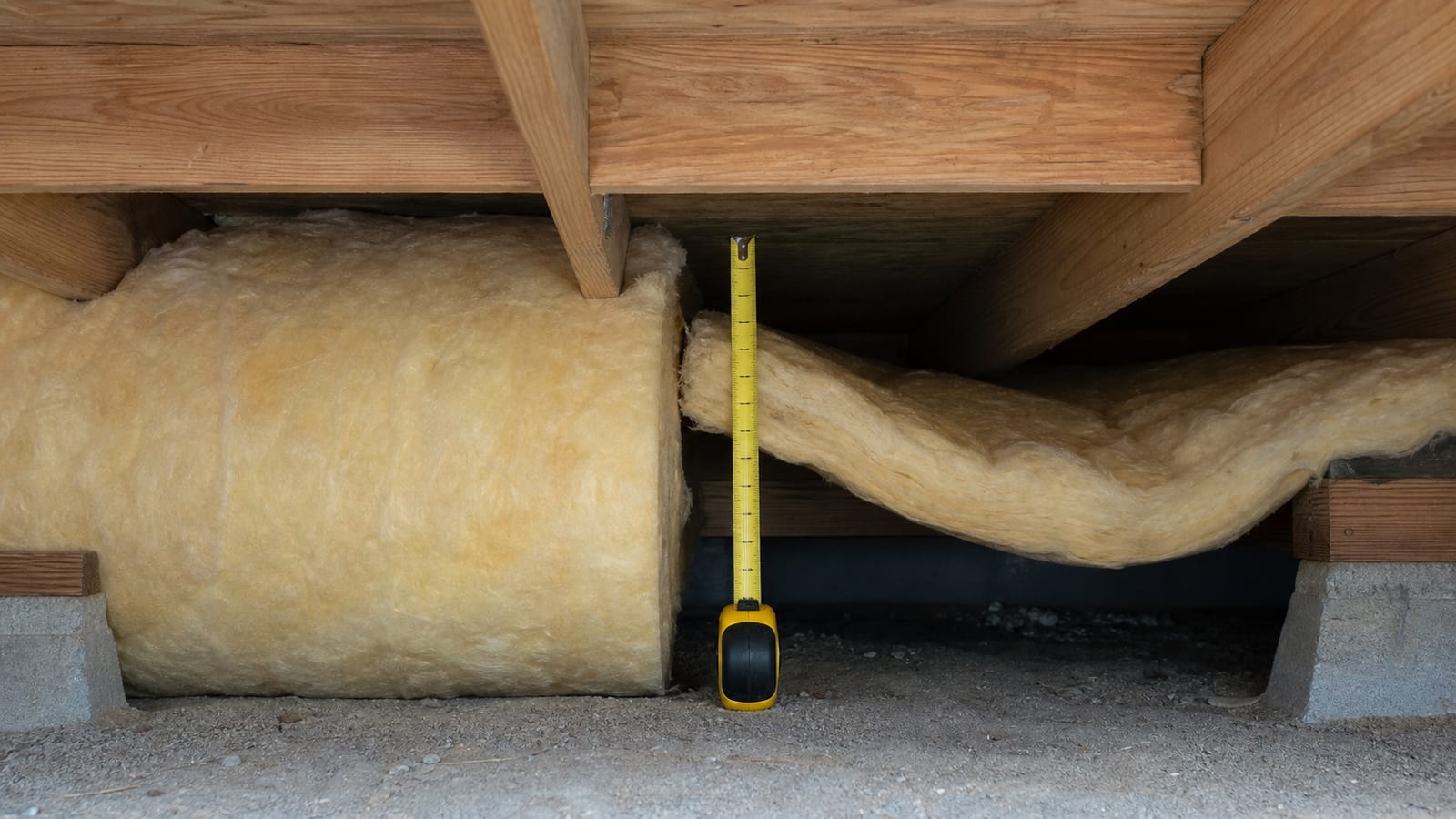 Crawl space insulation depth and framing conditions being measured beneath a floor