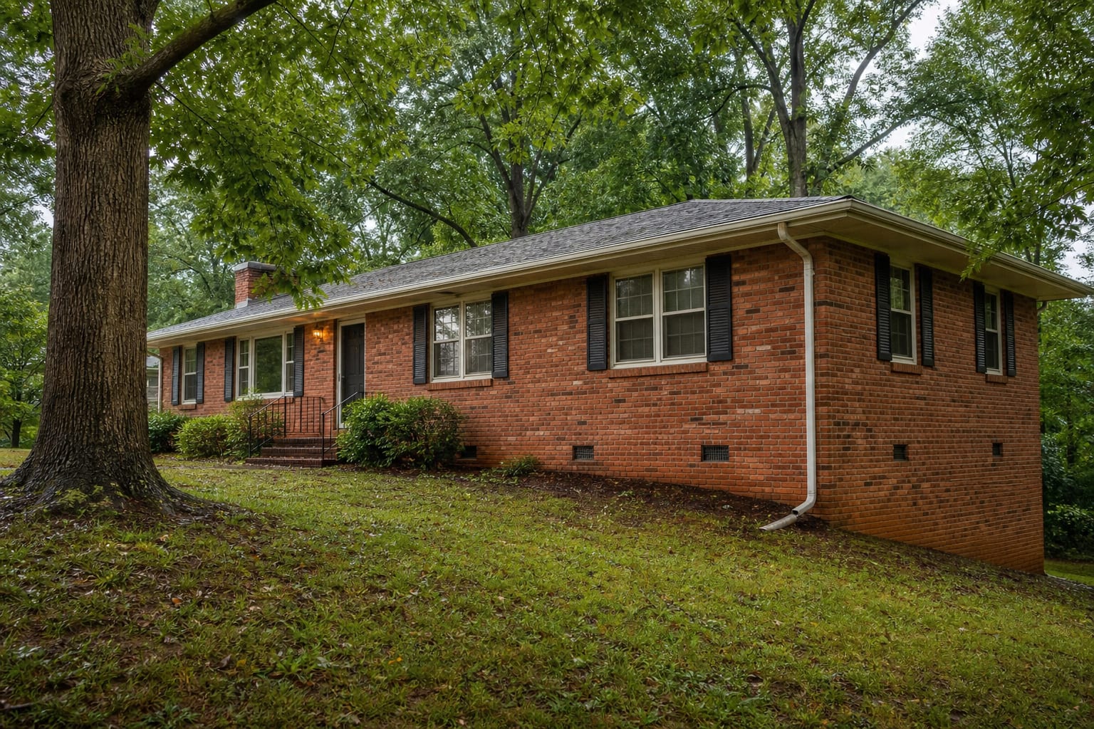 Mid-century brick ranch with crawl space vents and a downspout after rain